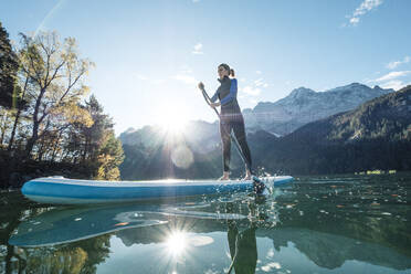 Germany, Bavaria, Garmisch Partenkirchen, Young woman stand up paddling on Lake Eibsee - WFF00477