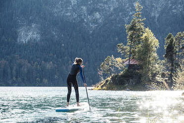 Germany, Bavaria, Garmisch Partenkirchen, Young woman stand up paddling on Lake Eibsee - WFF00489