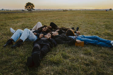 Junge männliche und weibliche Freunde liegen im Park im Gras - MASF22052