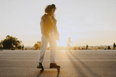 Young woman standing on skateboard in park - MASF22079