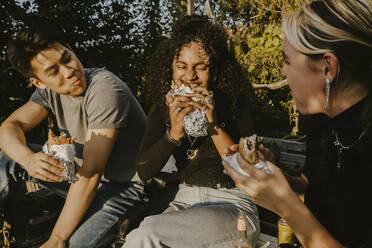 Young woman eating food with friends in park - MASF22092