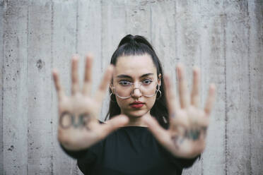 Our planet text written on palms of female activist against wall - MASF22161