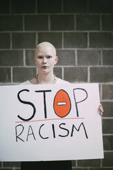 Junge Demonstrantin mit Stop-Rassismus-Schild an der Wand - MASF22205