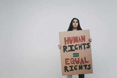 Female activist with human rights signboard against white wall - MASF22207