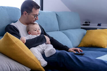 Vater benutzt Tablet, während er mit seinem kleinen Sohn auf dem Sofa im Wohnzimmer sitzt - AMPF00103