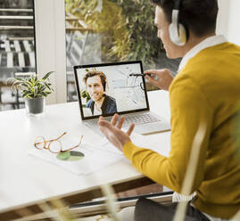 Businessman attending video conference while sitting at home office - UUF22878