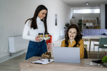 Lächelnde Frau, die einer zu Hause arbeitenden Mutter Kaffee serviert - GIOF11458