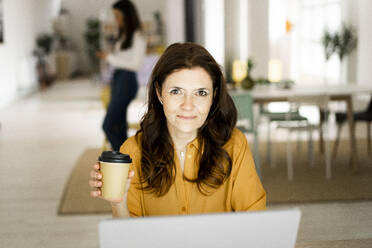 Businesswoman holding coffee cup at home office - GIOF11461