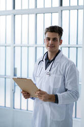 Male doctor holding clipboard in hospital - GIOF11523