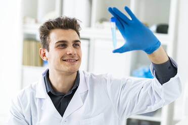 Smiling male scientist examining liquid in test tube - GIOF11531