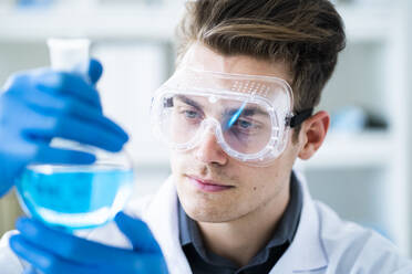 Handsome male scientist examining chemical in laboratory - GIOF11545