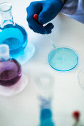 Wissenschaftlerin, die eine Chemikalie in einer Petrischale mit Hilfe einer Pipette im Labor mischt - GIOF11547