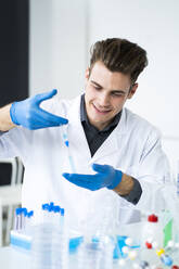 Männlicher Wissenschaftler, der im Labor ein Medikament in ein Reagenzglas injiziert - GIOF11572