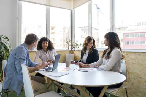 Männliche und weibliche Kollegen diskutieren, während sie am Schreibtisch im Büro sitzen - AFVF08342