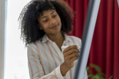 Young businesswoman writing on flipchart at office - AFVF08354