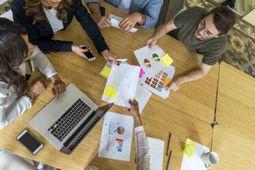 Unternehmerinnen, die sich bei einem Treffen im Büro gegenseitig Strategiepapiere übergeben - AFVF08410