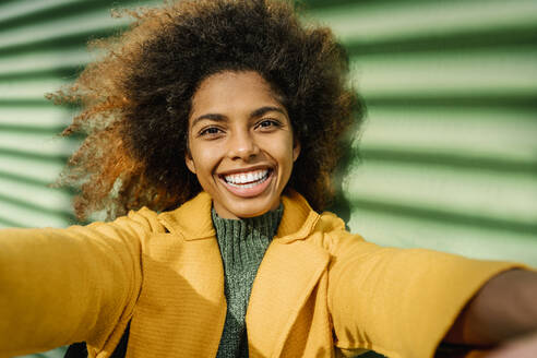 Schöne Afro-Frau nimmt Selfie gegen grüne Wand - EGAF01987