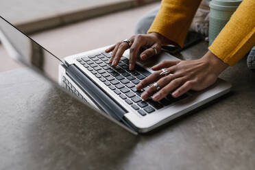 Frau arbeitet am Laptop, während sie auf dem Boden sitzt - EGAF01998
