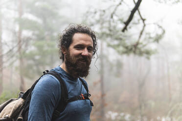 Portrait of bearded hiker smiling at camera - JAQF00349