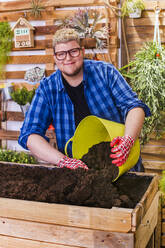 Junger Mann bereitet das Substrat für einen städtischen Garten aus Paletten auf seiner Terrasse vor - RTBF01563