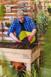 Junger Mann bereitet das Substrat für einen städtischen Garten aus Paletten auf seiner Terrasse vor - RTBF01564