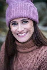 Porträt einer schönen Frau mit rosa Strickmütze, die in die Kamera lächelt - AKLF00113
