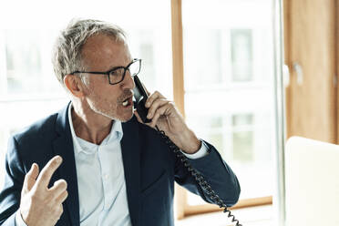 Worried businessman talking on telephone in office - GUSF05346