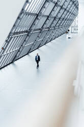 Senior male business professional walking in office corridor - GUSF05457