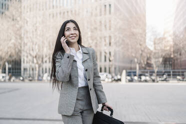 Smiling businesswoman talking on smart phone in city - JCZF00470