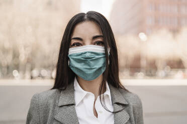 Businesswoman with protective face mask in city during COVID-19 - JCZF00475