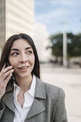 Thoughtful businesswoman talking on smart phone in city - JCZF00482