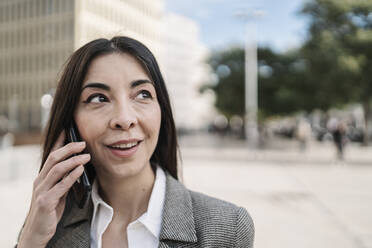 Nachdenkliche Geschäftsfrau, die in der Stadt mit einem Smartphone telefoniert - JCZF00483