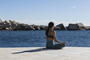 Young woman meditating on promenade during sunny day - PNAF00892