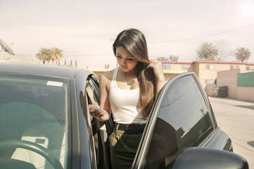 Junge Frau telefoniert neben einem Auto in der Stadt - AJOF01161