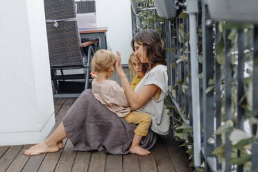 Mother with her little son and daughter sitting on terrace  - OGF00926