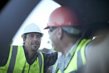 Two male construction workers chatting by car - AJOF01182