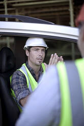 Zwei männliche Bauarbeiter unterhalten sich im Auto - AJOF01183