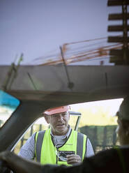 Zwei männliche Bauarbeiter unterhalten sich im Auto - AJOF01184