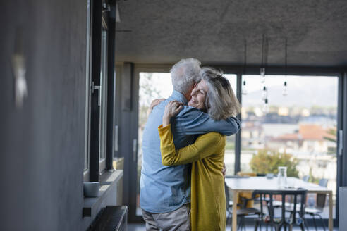 Senior woman smiling while embracing man at home - EIF00437