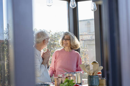 Senior couple looking at each other while standing at home - EIF00469