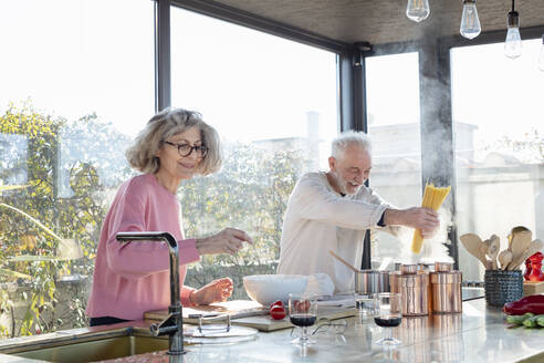 Senior couple cooking together in kitchen at home - EIF00476