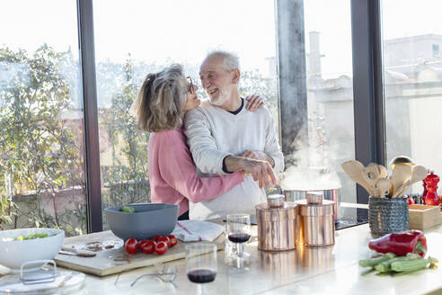 Woman with arm around on man smiling while standing at home - EIF00479