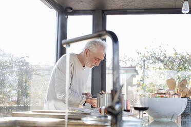 Senior man cooking while standing in kitchen at home - EIF00480