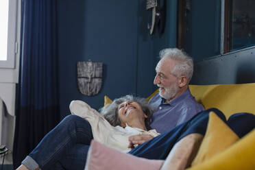 Happy senior couple resting on sofa at home - EIF00508