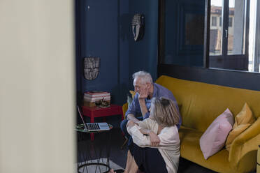 Älteres Ehepaar, das zu Hause sitzend ein Videogespräch über einen Laptop führt - EIF00510