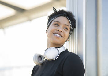 Young woman looking away while leaning on wall - JCCMF01327