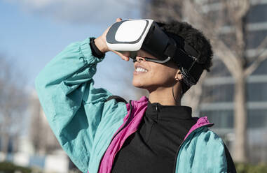Glückliche Frau mit Virtual-Reality-Headset in der Stadt - JCCMF01335
