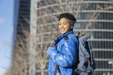 Happy young woman with backpack in city on sunny day - JCCMF01339