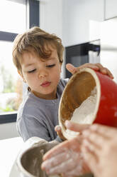 Boy pouring flour in electric mixer at kitchen - IFRF00432
