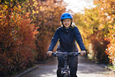 Glückliche Frau mit Helm auf dem Fahrrad im Park - PSIF00454